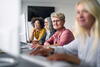 a group of people n front of computers taking a course